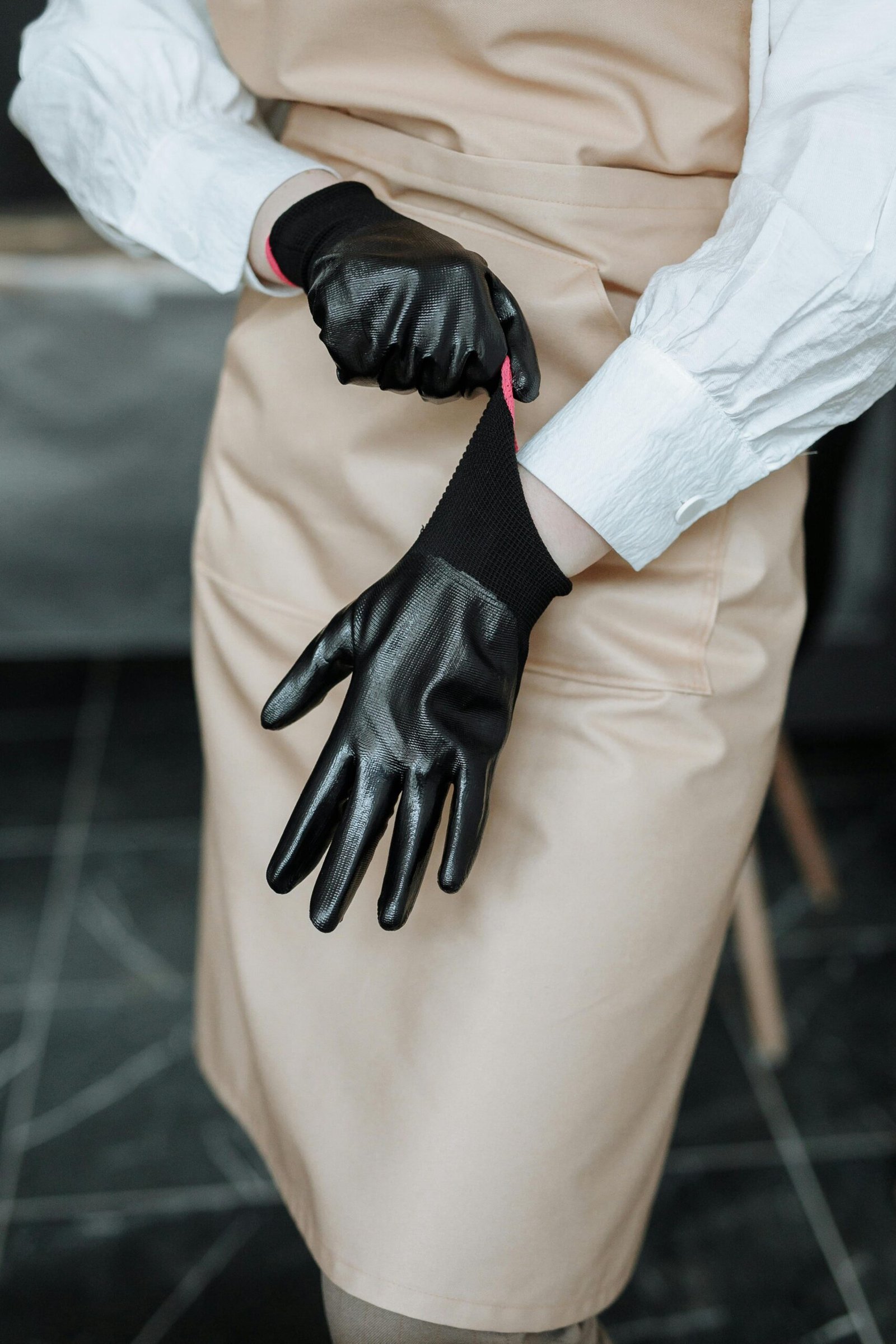 Factory worker wearing brown leather gloves operating industrial equipment in a workshop setting.